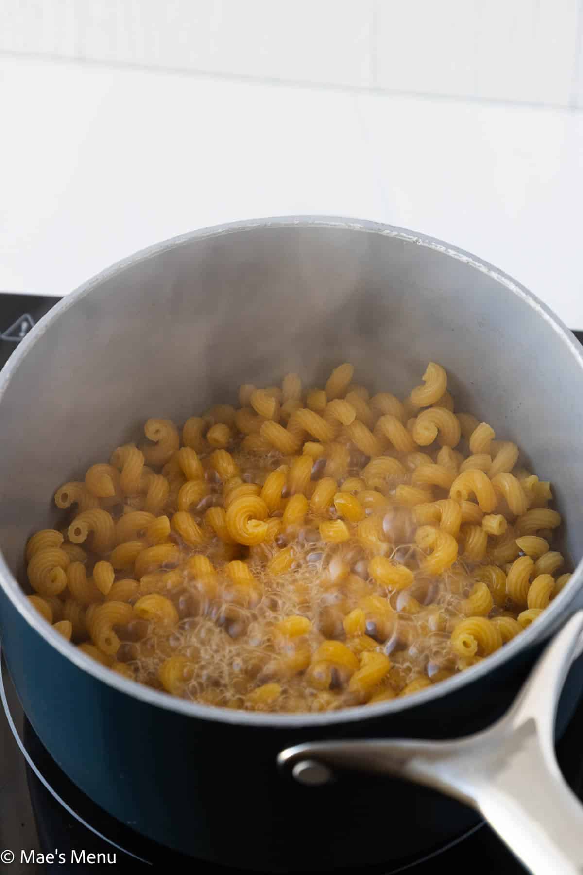 the macaroni boiling in bone broth in a saucepan.