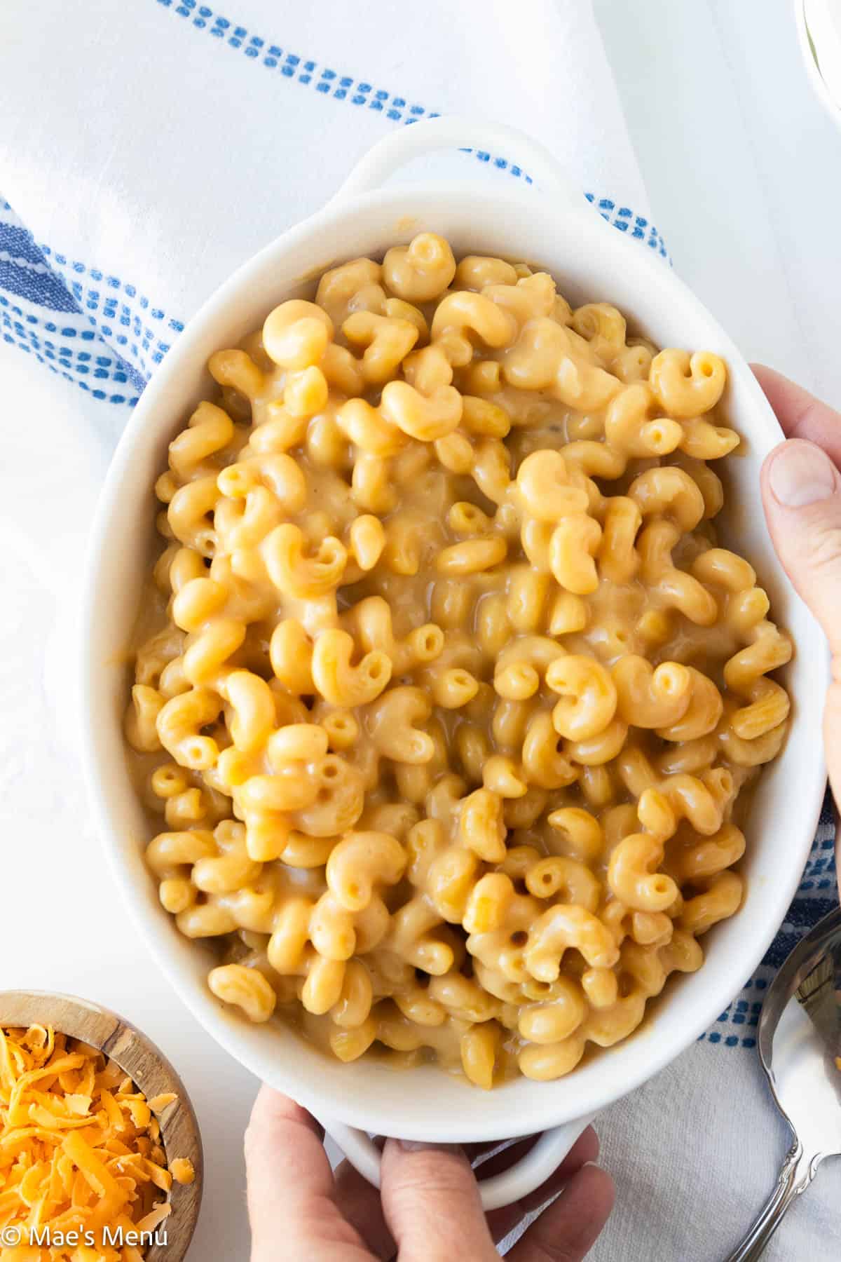An overhead shot of two hands holding a serving bowl of high-protein mac and cheese.