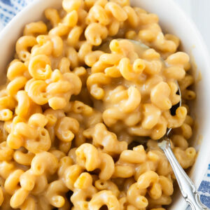 A close-up shot of a bowl of high-protein mac and cheese in a bowl with a serving spoon.