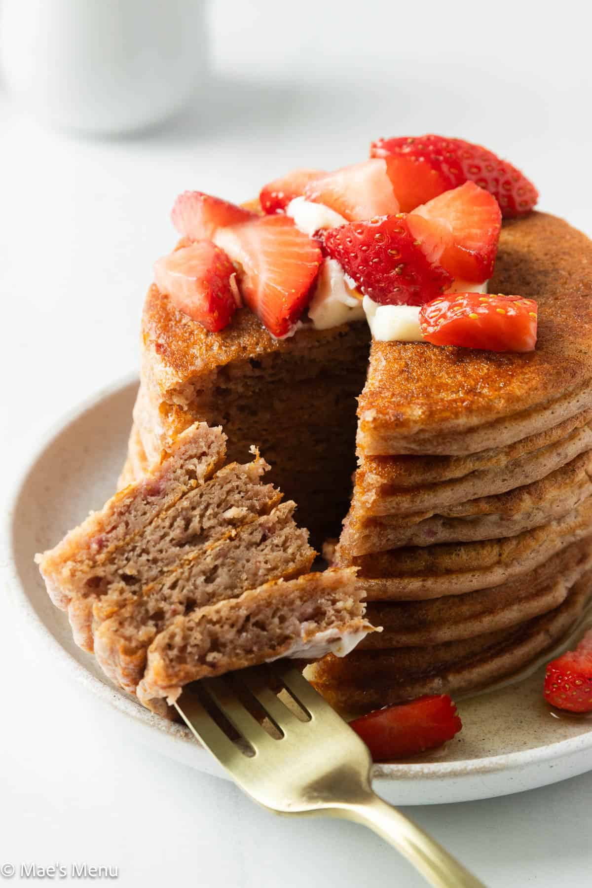 A close-up shot of high-protein strawberry pancakes with a wedge taken out of them.
