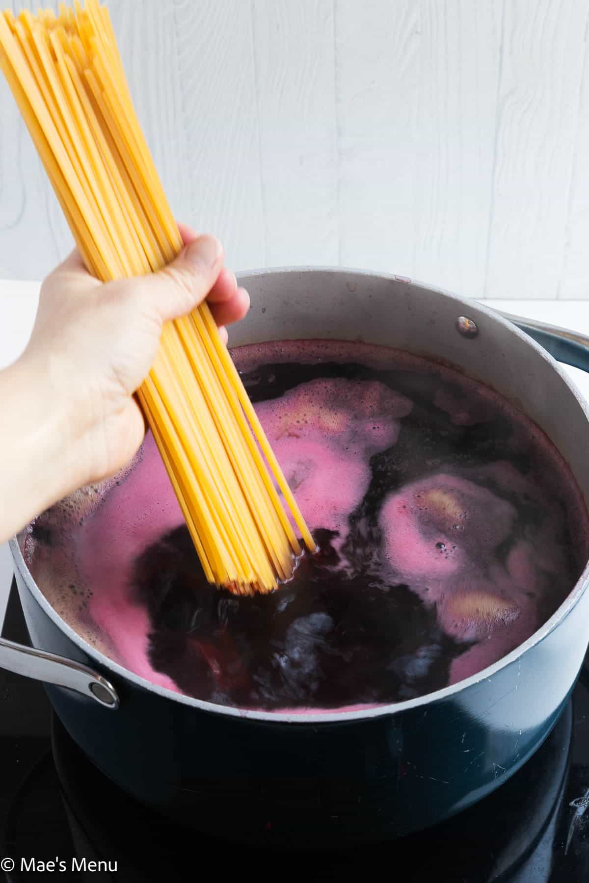 Adding pasta to a pot of beets boiling in water and red wine.