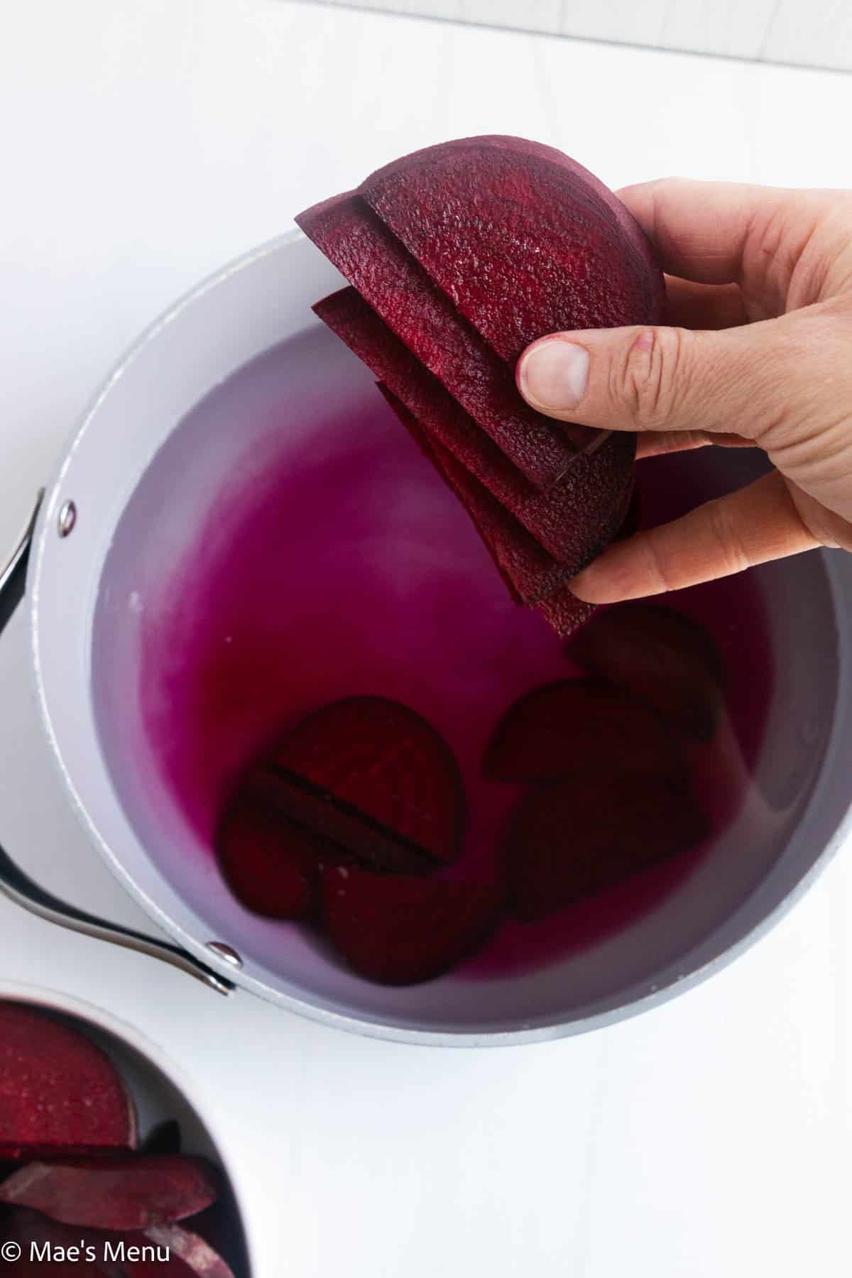 Adding beets to a large pot of waer.