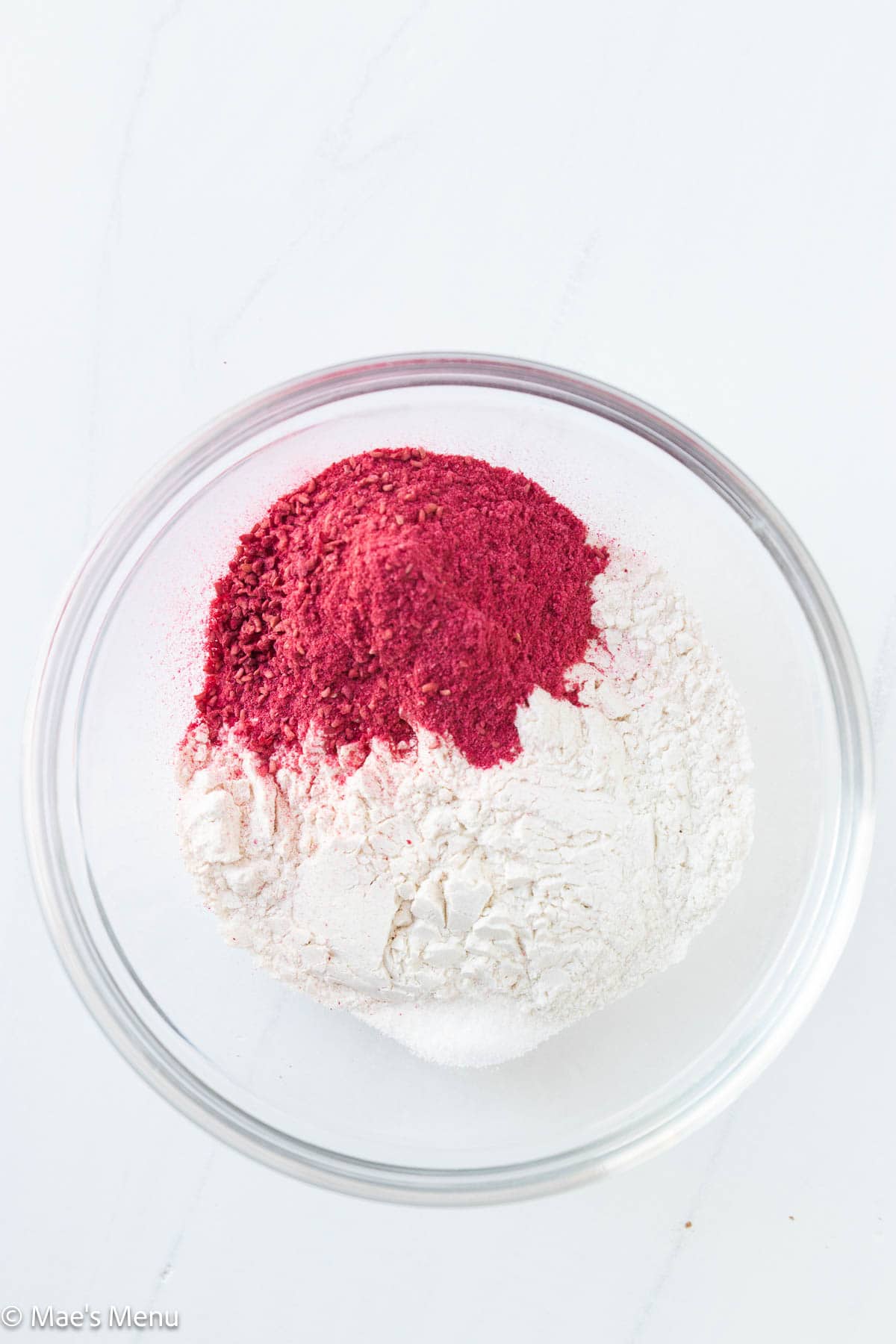 A small mixing bowl of raspberry powder, flour, and salt.