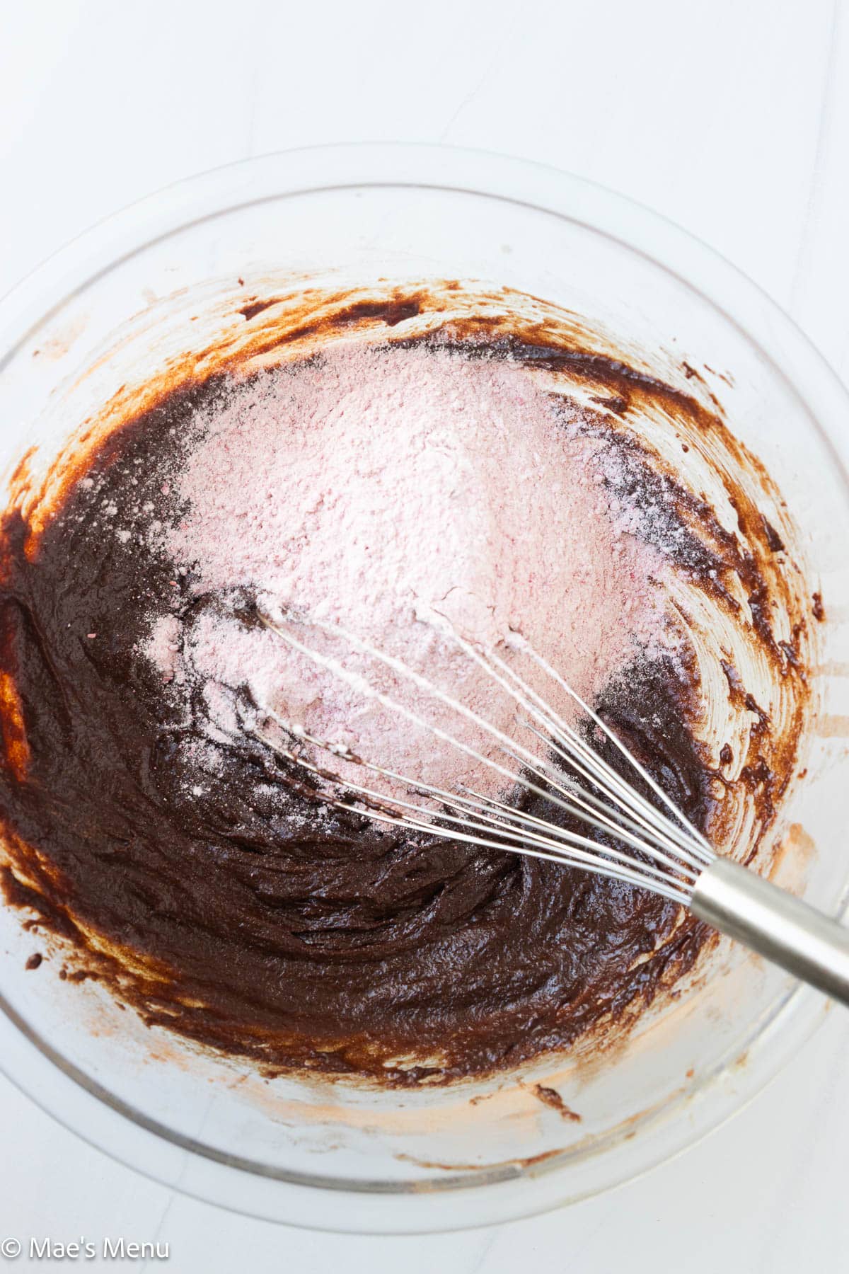 Adding the raspberry flour mixture to the bowl of brownie batter.