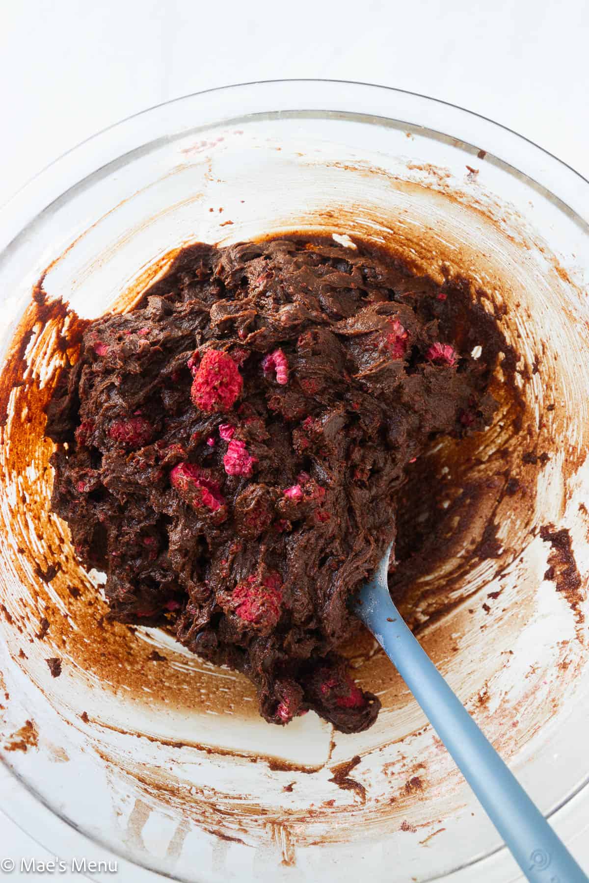 The raspberry brownie batter in a mixing bowl with a spatula.