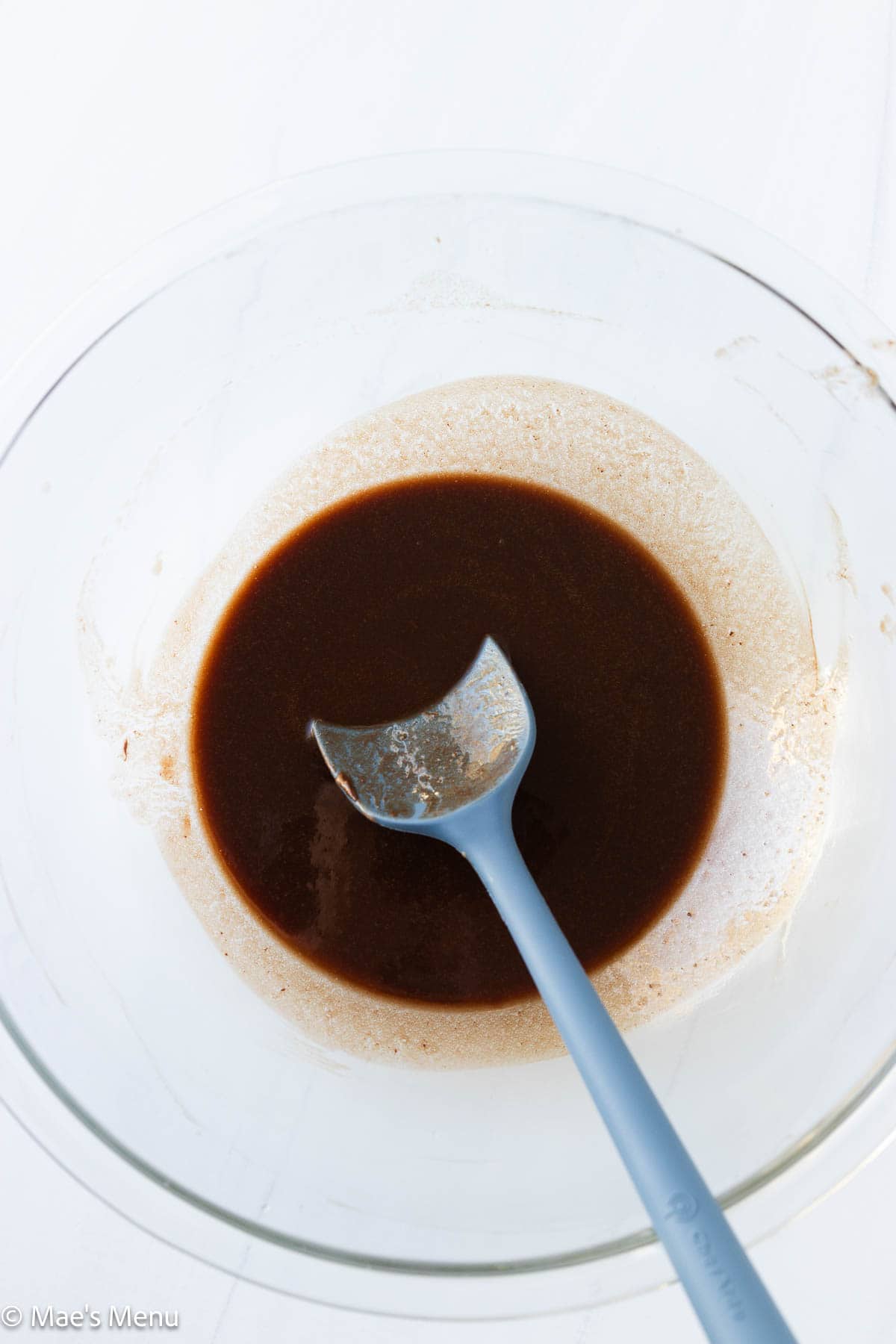 An overhead shot of melted chocolate and butter in a mixing bowl with a spatula.