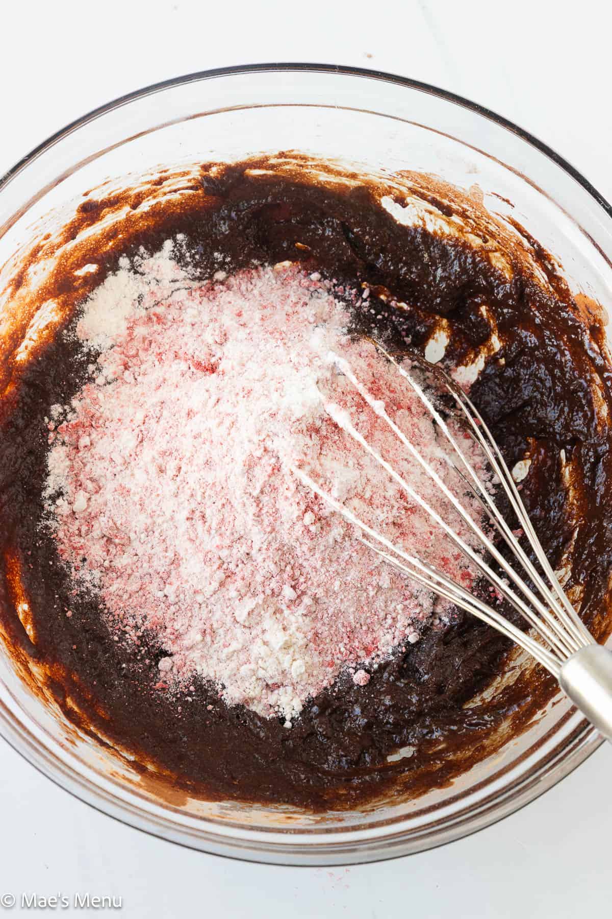 Adding the strawberry and flour mixture to the bowl of brownie batter.