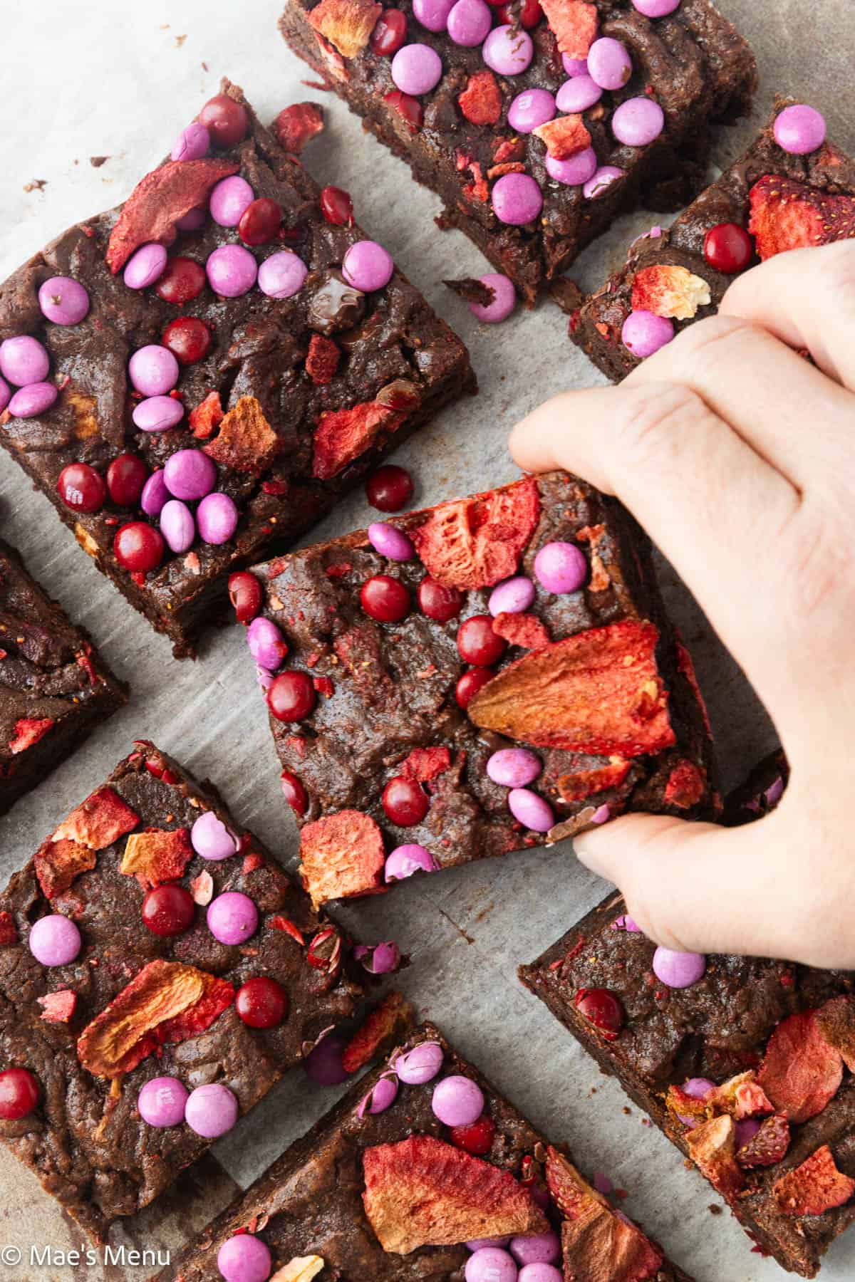 Grabbing a strawberry brownie from the pan of cut up strawberry brownies.