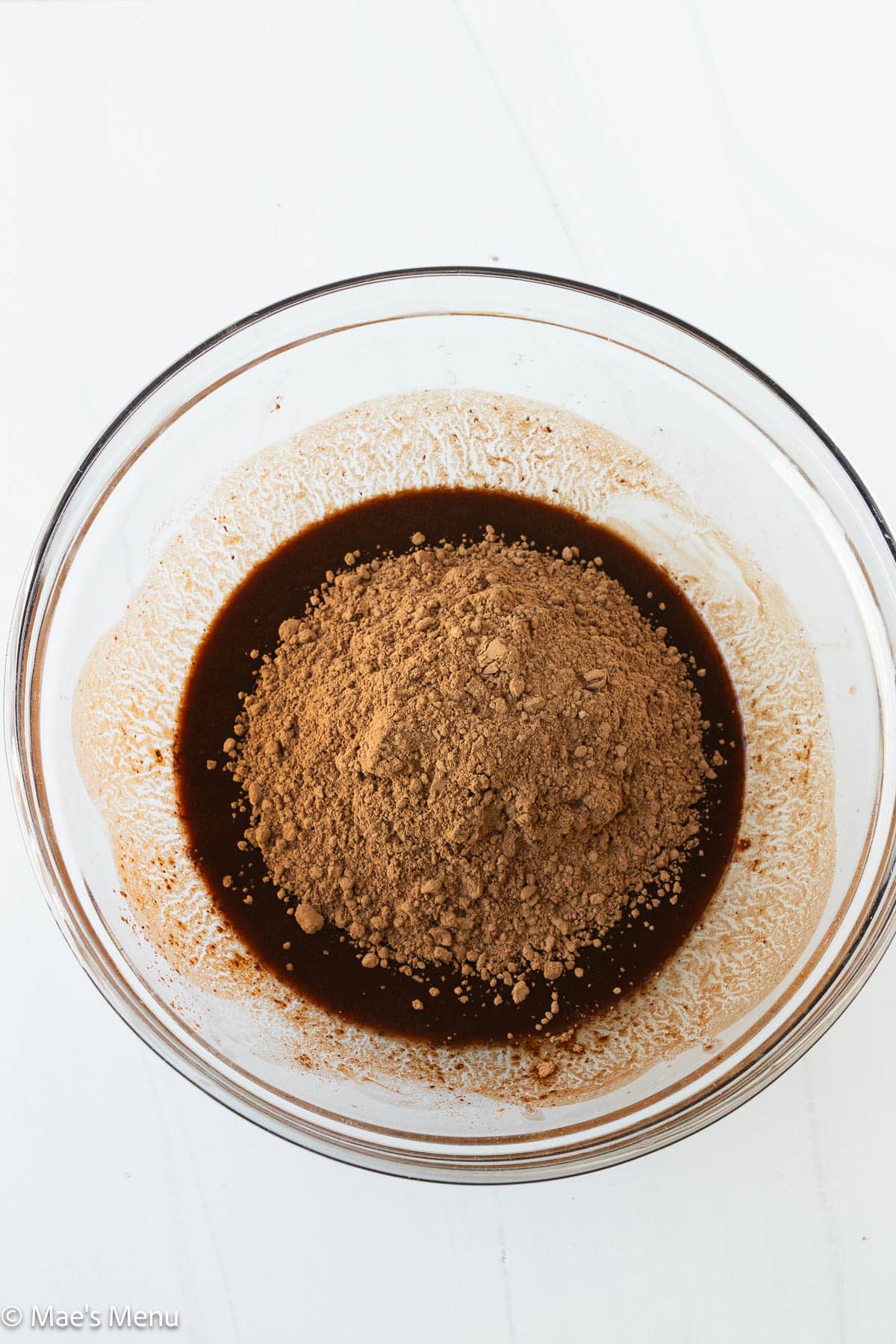 The cocoa powder added to the bowl of melted chocolate and butter.