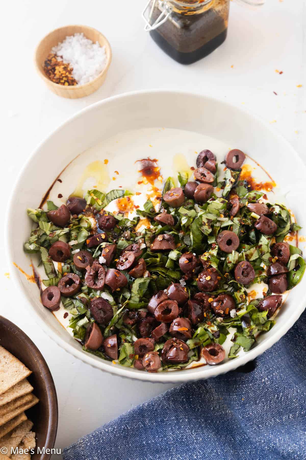 An elevated shot of a bowl of whipped cottage cheese topped with basil and olives.