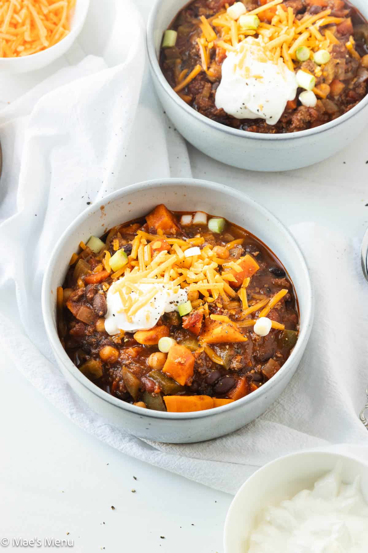 Two bowls of Bison chili with toppings on the counter.