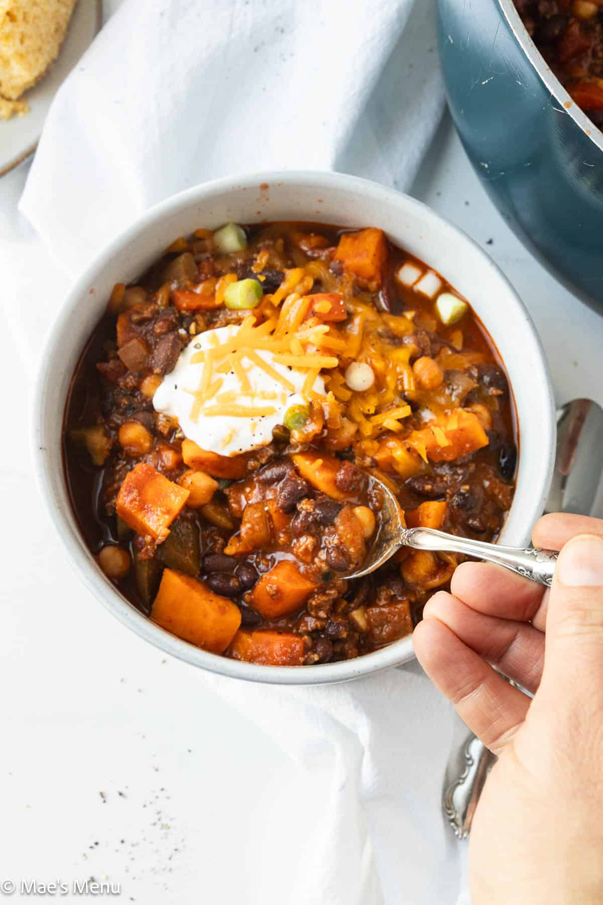 A hand grabbing a serving of bison chili.