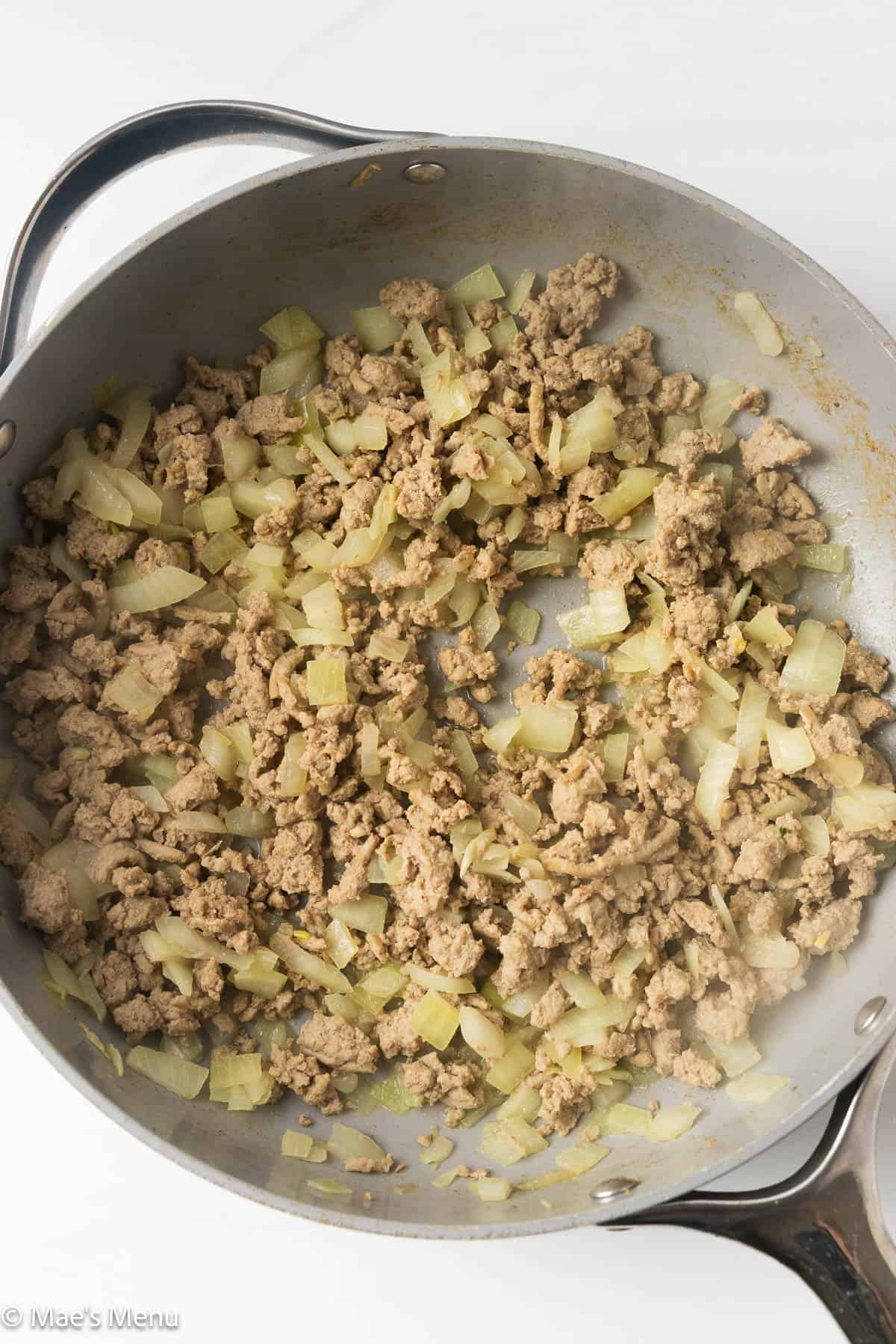 An overhead shot of the browned meat and onions in a skillet.