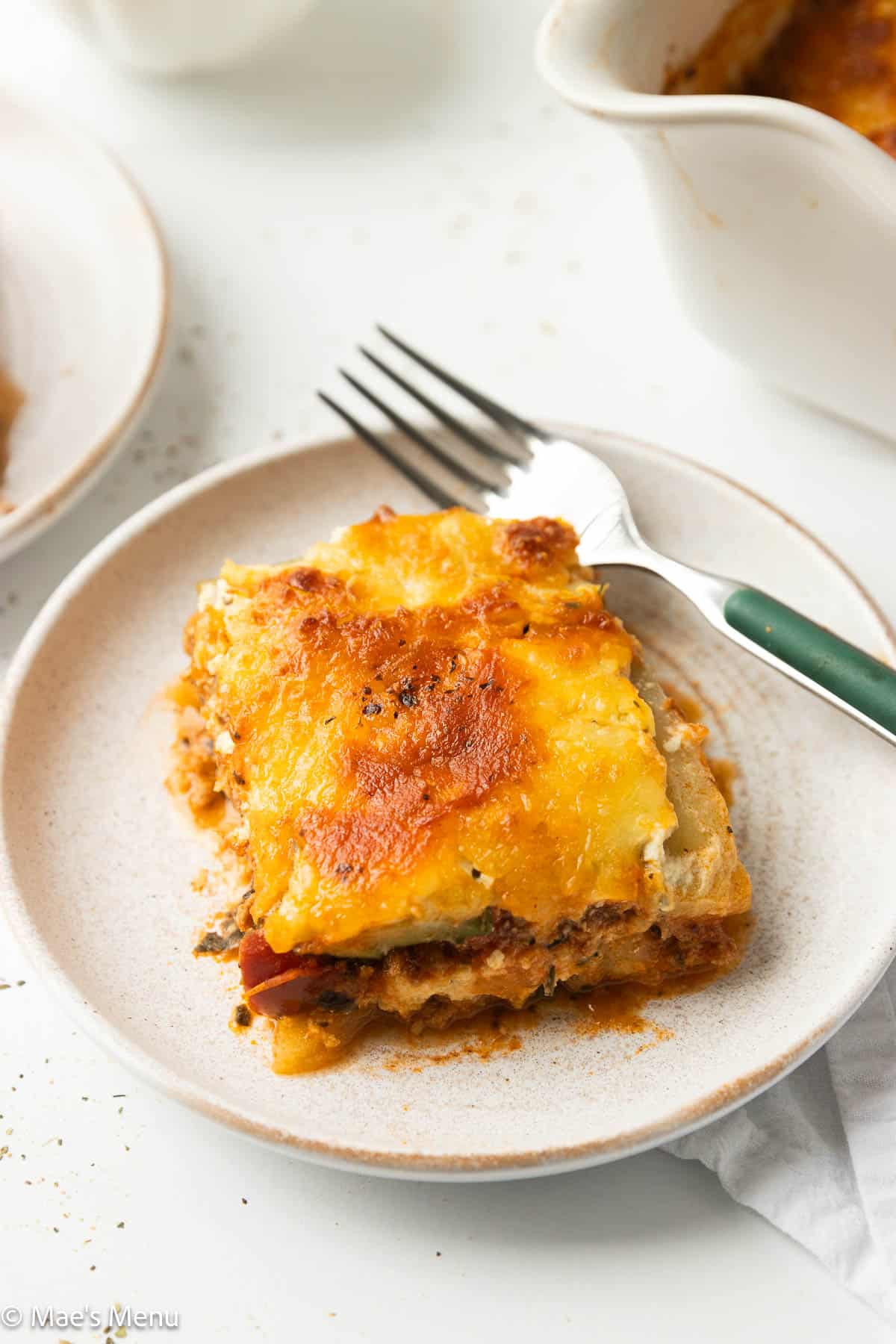 An overhead angled shot of a piece of zucchini lasagna on a small plate with a fork.