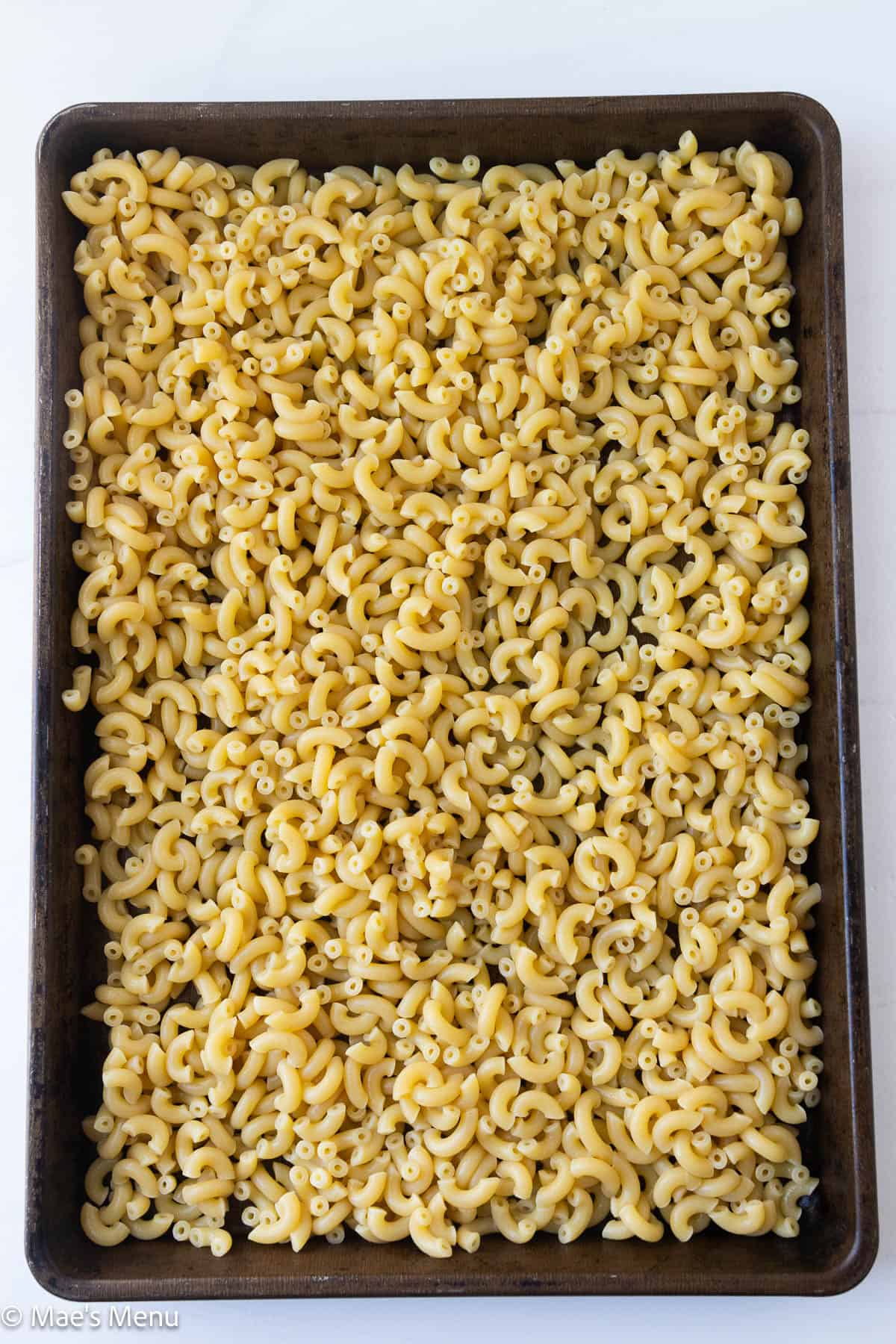 An overhead shot of a sheet pan of cooling tuna pasta salad.