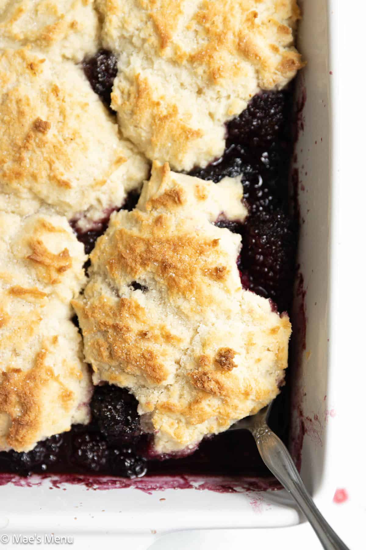 A close-up overhead shot of blackberry cobbler in a pan with spoons.