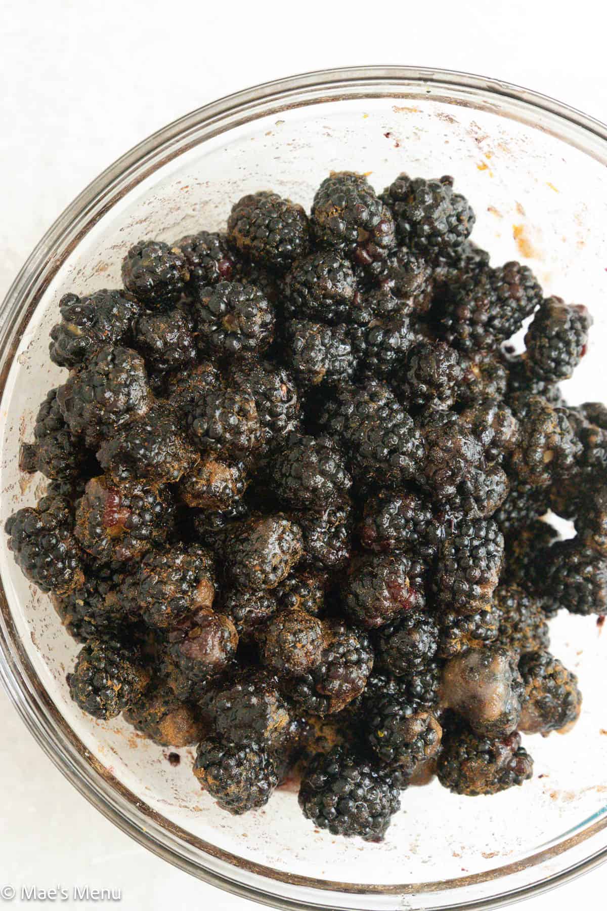 A close-uo overhead shot of a bowl of blackberries tossed in sugar, flour, and lemon zest.