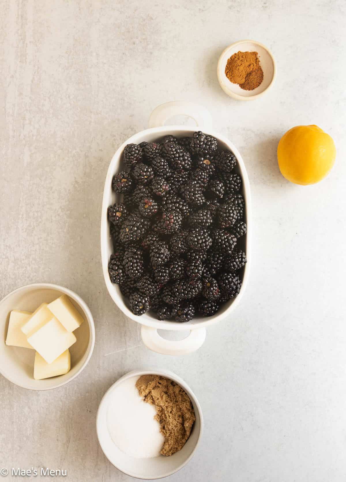 The berries, lemon, spices. sugar , and butter on the counter.